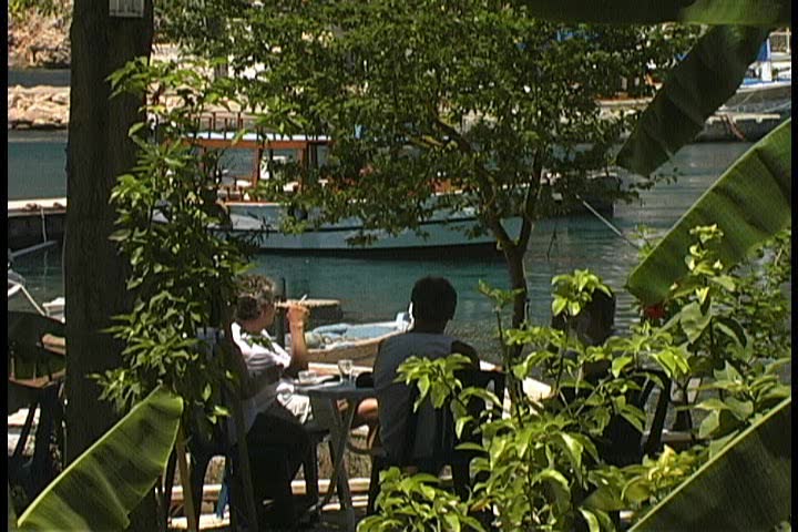 People eating at an outdoor restaurant on the harbor