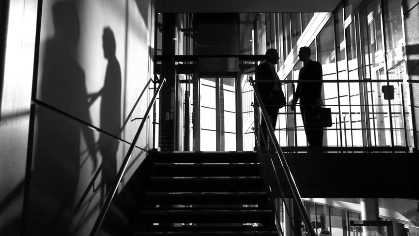 Business colleagues shake hands in this video clip of shadows meeting in large offices.