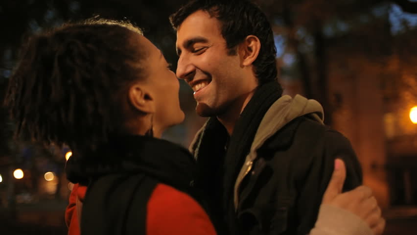 A young couple hug and kiss each other in a city Park. Close up shot.