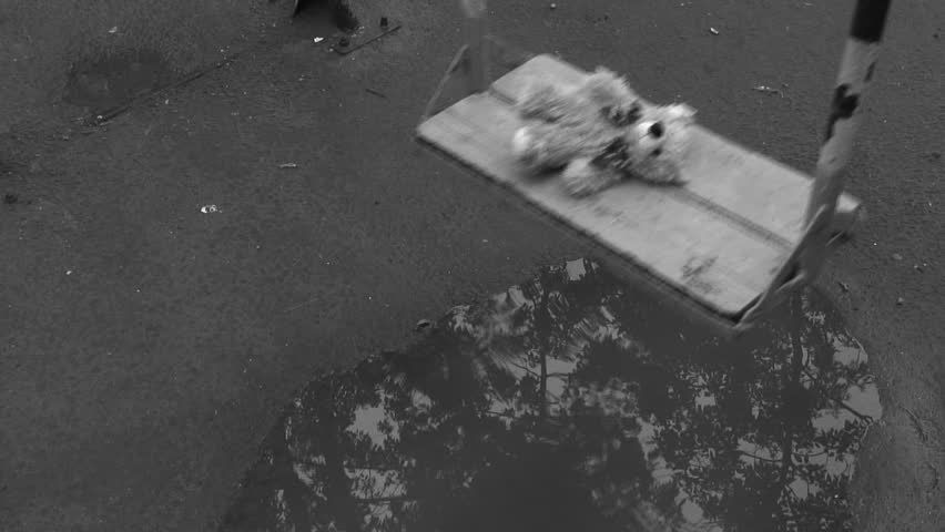 Forgotten Teddy bear on a swing under rain. Deep depression theme. Black and white.