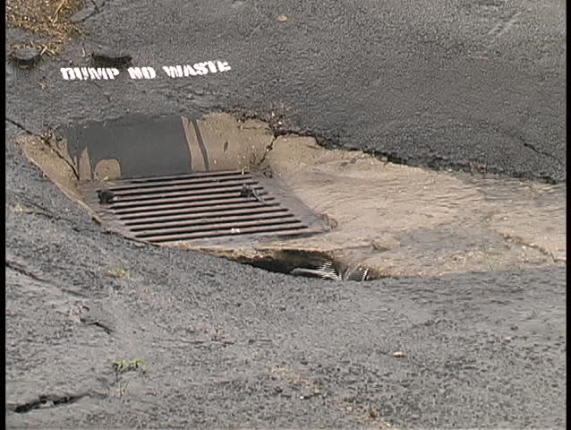 Water from a heavy rain flows quickly into an outdoor drain.