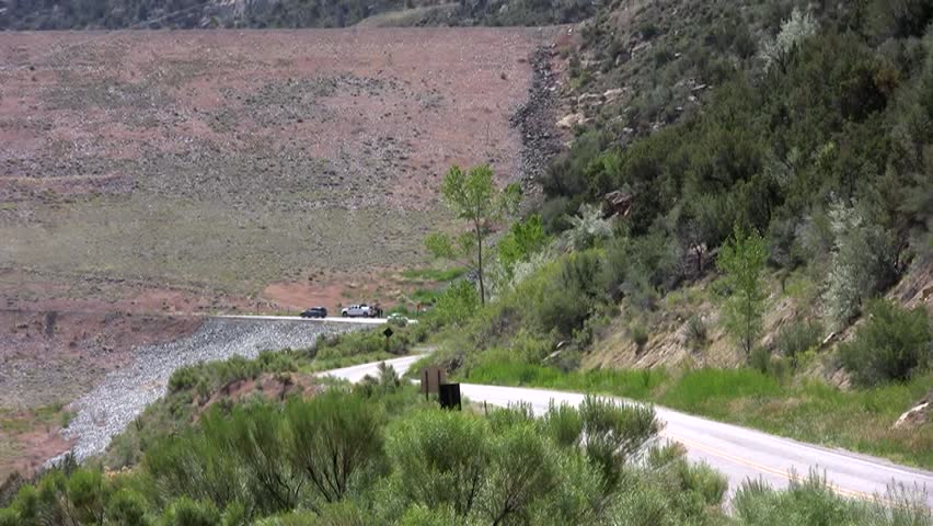 HD clip of a pair of flatbed trucks coming loudly off the face of Navajo Dam in northern New Mexico