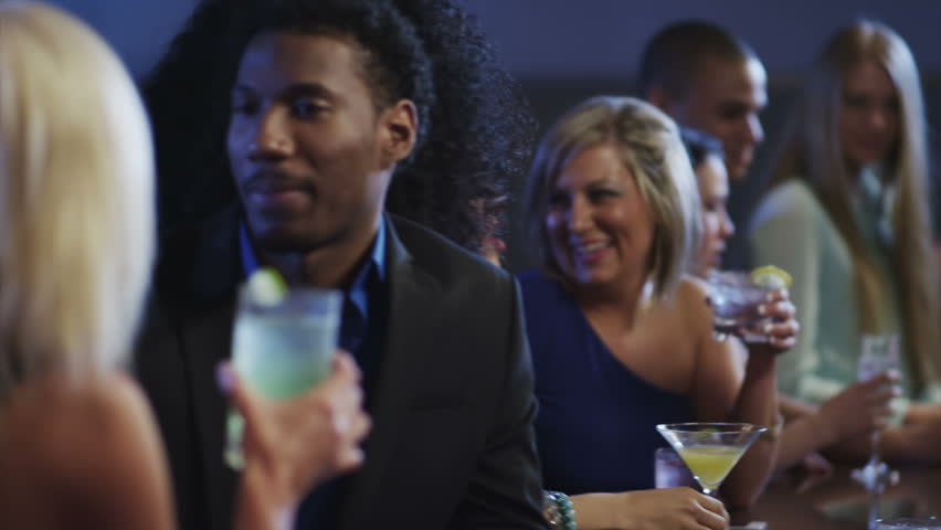 People have conversations while hanging out at the bar in a night club