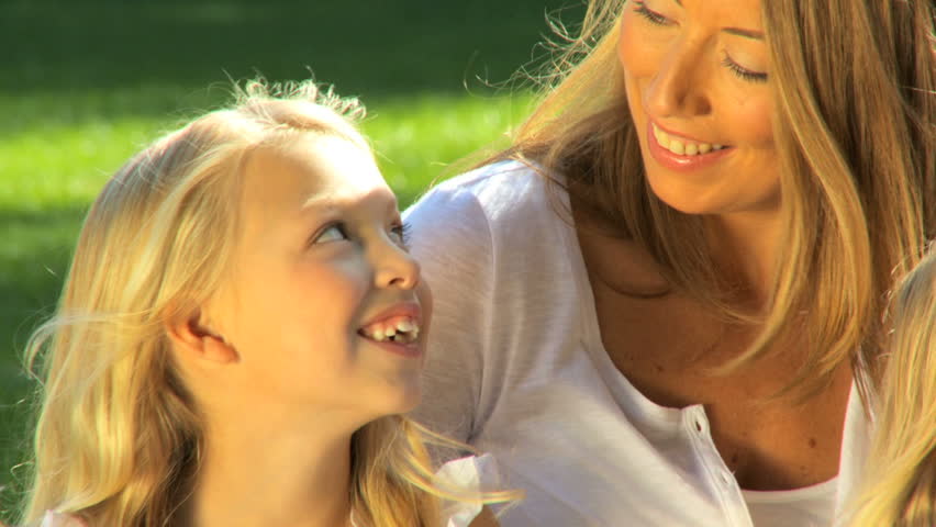 Attractive mother tenderly talking to her daughter while outdoors on a summers day