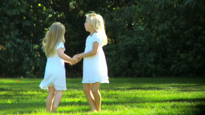 Young child sisters having fun together outdoors on a summers day