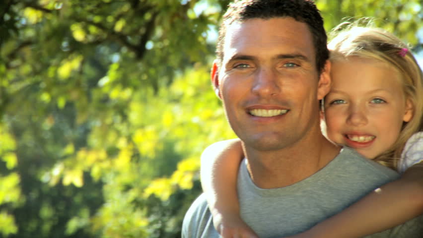 Young father tenderly holding his daughter while outdoors on a summers day