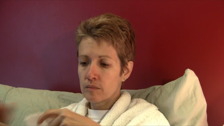 Sick woman sneezing into tissue from side