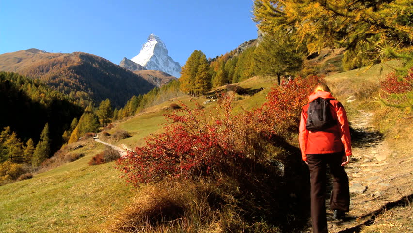 Fall in an alpine meadow, Zermatt, with female hiker & the Matterhorn, motion jib