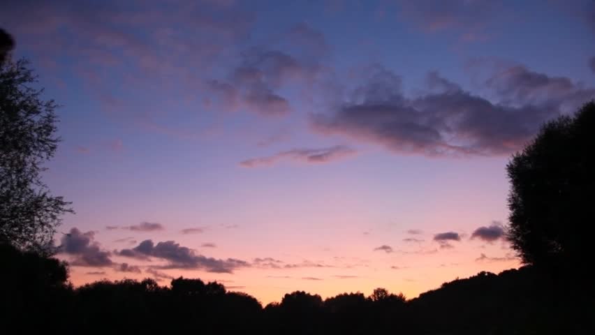 traveler with rucksack looks at sunset and lifts hands 