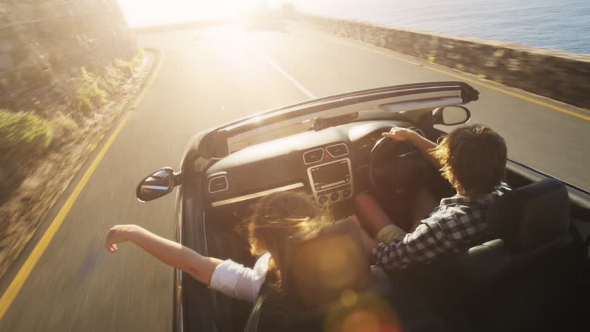 Couple driving convertible car cabriolet cape town south africa steadicam shot with flare