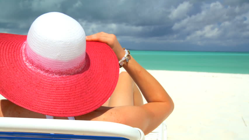 Elegant young female relaxing on white sandy beach looking at aquamarine waters 60 FPS