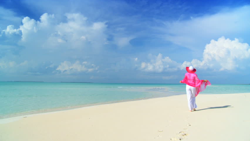 Elegant young female on a beautiful white sandy beach looking at aquamarine waters 60 FPS
