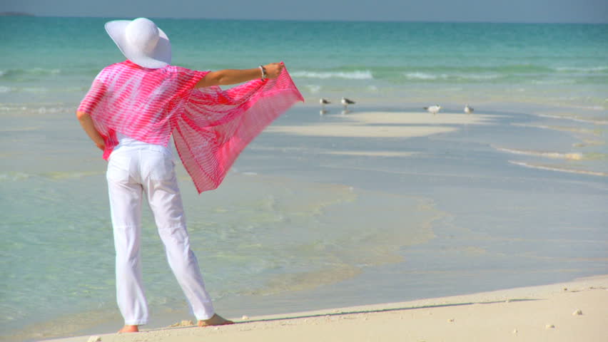 Elegant young female on a beautiful white sandy beach looking at aquamarine waters 60 FPS