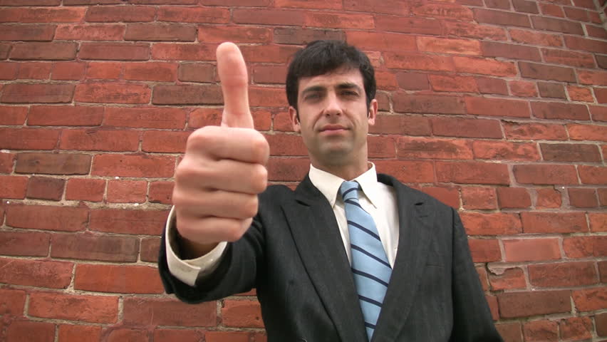 Thumbs up, then down. A businessman turns his thumb from up to down, in a gesture of denial. 