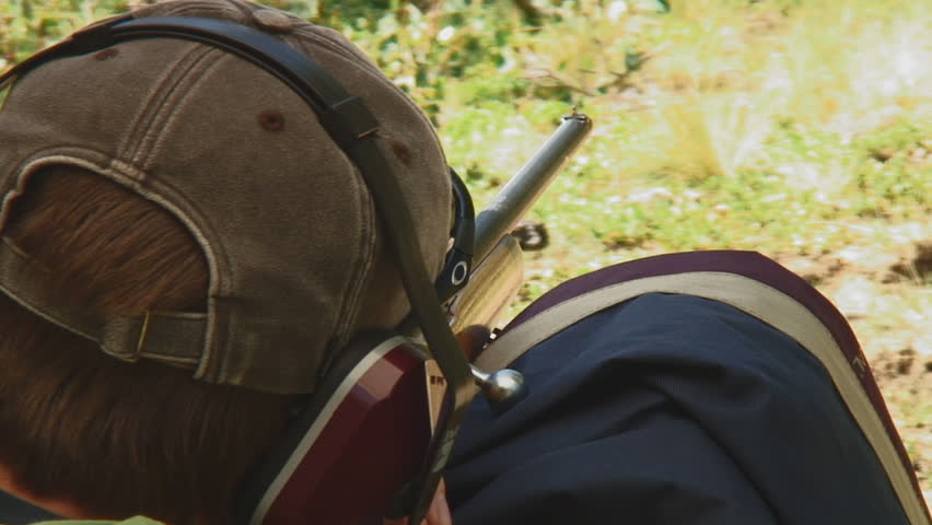 young sportsman fires vintage .22 caliber rifle, checks target and returns to shoot again