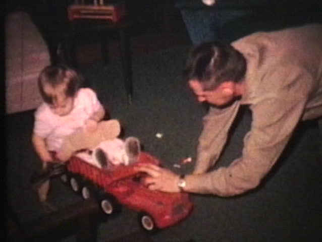 A young father does some playing and rough housing with his little boy and little girl in the living room.