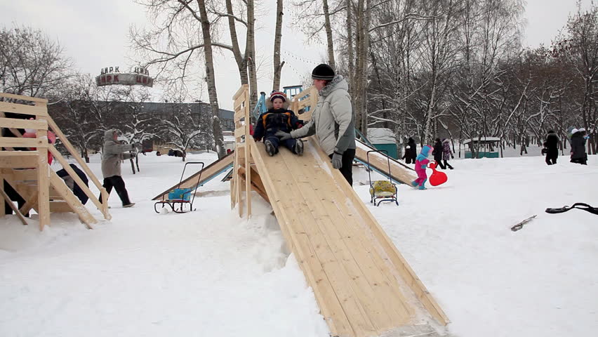 Mother and child play on a slide in a playground