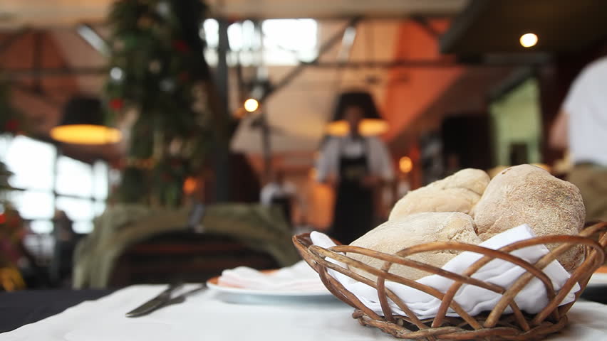 Table setting in restaurant with bread, empty glass and waiters 
