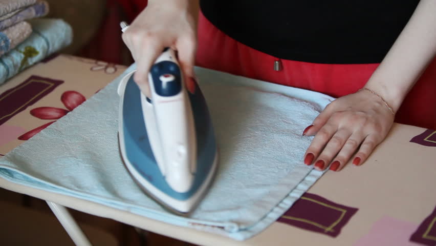 Young woman ironing towel.