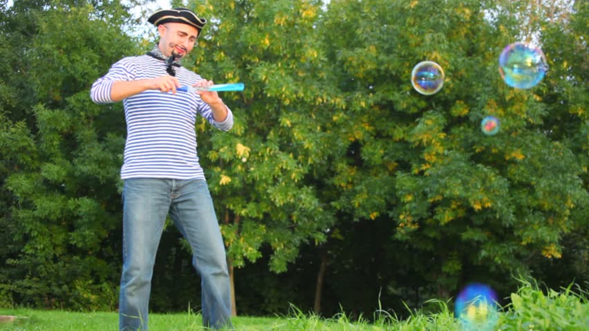 man in pirate costume makes soap bubbles in park 