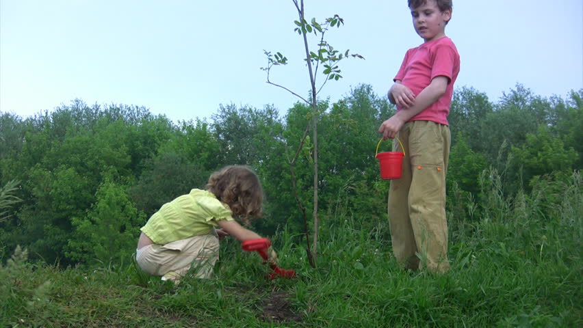 girl with shovel digging, boy with bucket watering young plant 