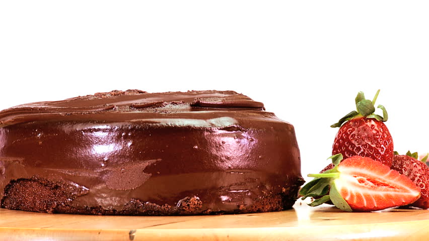 A serving of indulgent sticky chocolate cake served with fresh strawberries
