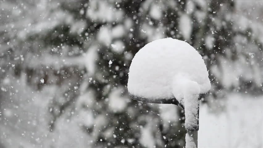 Snow falling heavily on a street lamp