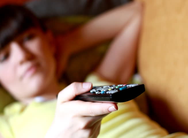 Dolly shot of Woman on a sofa with a tv remote control  - NTSC