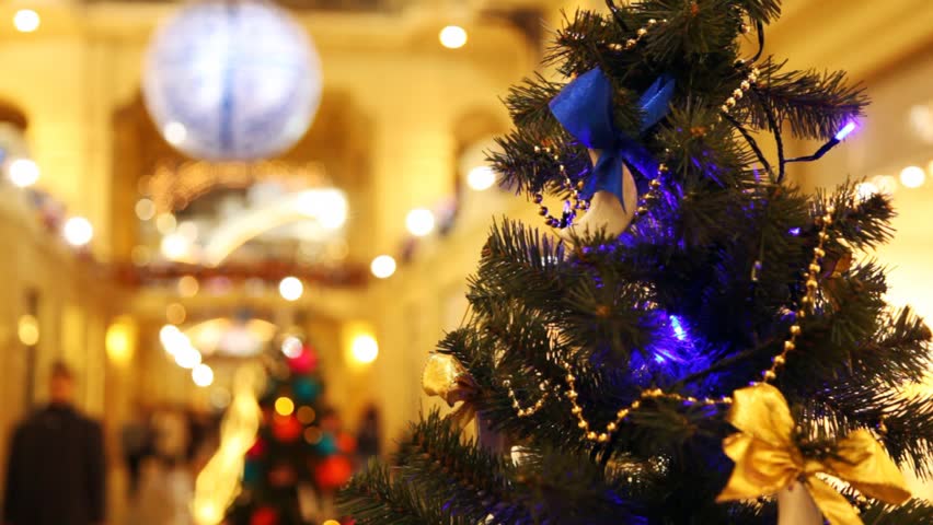 close up New Year's tree with blinking dark blue garlands in shopping centre 