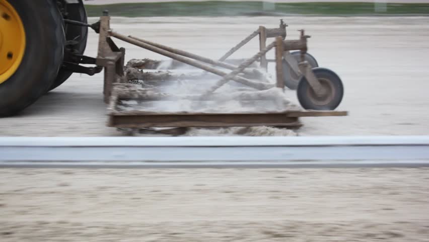 tractor with special plough goes on hippodrome track levelling it 
