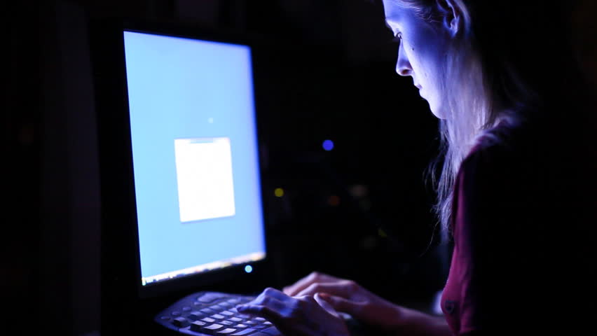 Young woman in front of computer screen. Dark night room. 
