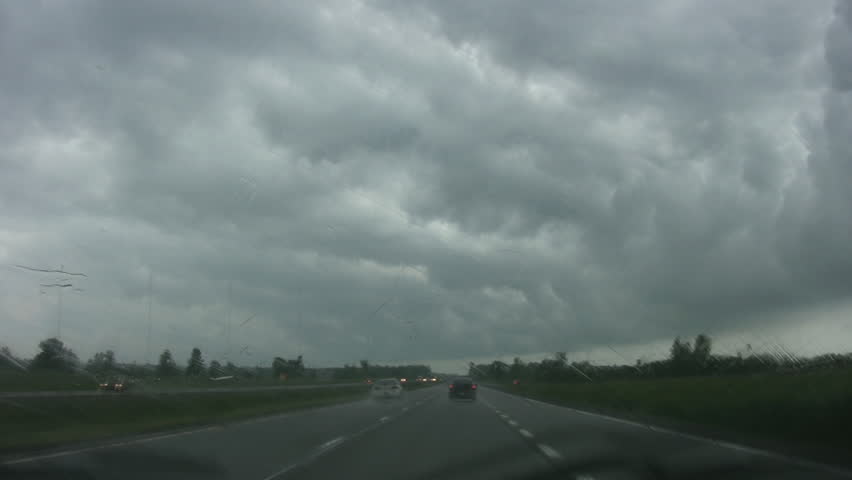 Driving into rainstorm. Highway driving with heavy rain on window. Stormclouds ahead.  