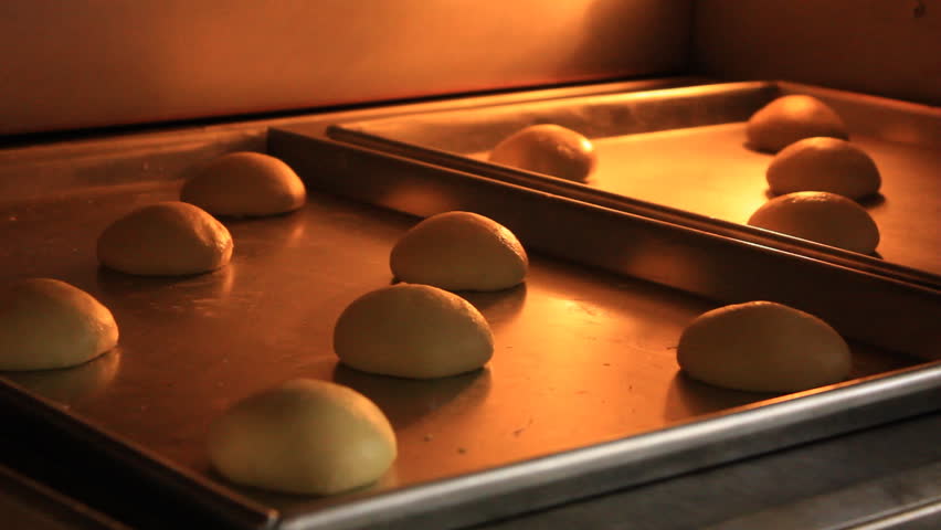 Bread rolls inside an oven, a chef then close the lid. 