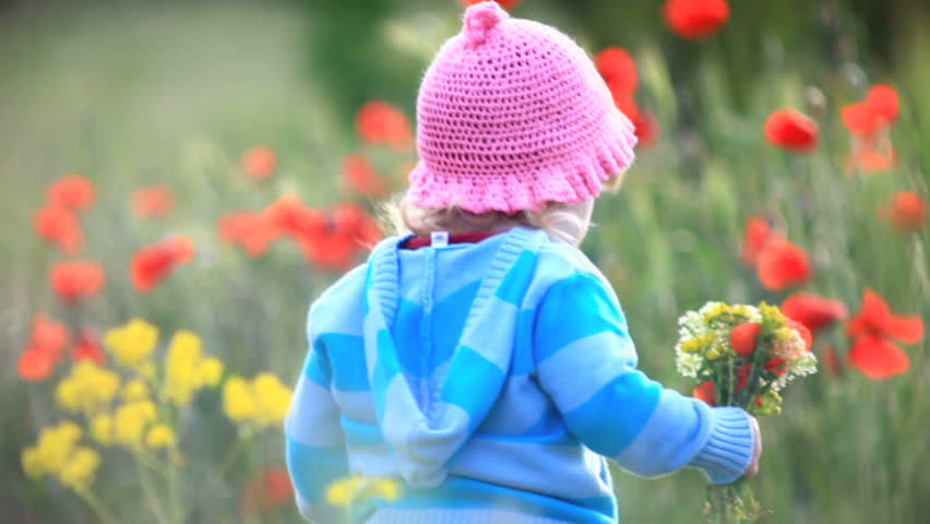 Child spinning with flowers in their hands. He looks into the camera