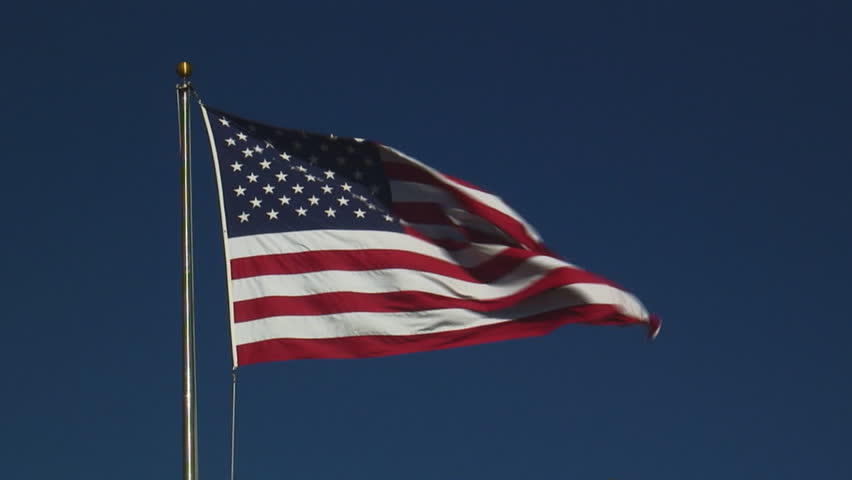 real United States of America flag flying on flagpole against clear blue sky - HD, no audio, medium shot