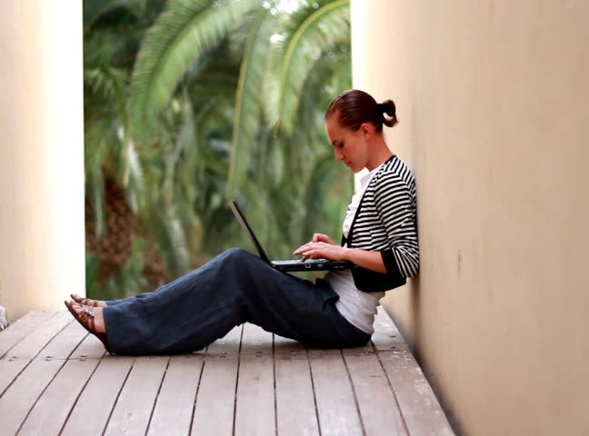 Woman with laptop sits outdoor