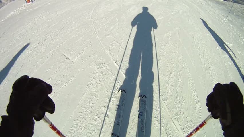 Silhouette of man skiing down slope