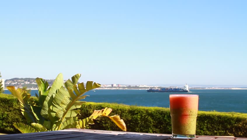 A glass of kiwi and strawberry juice and a sea-view