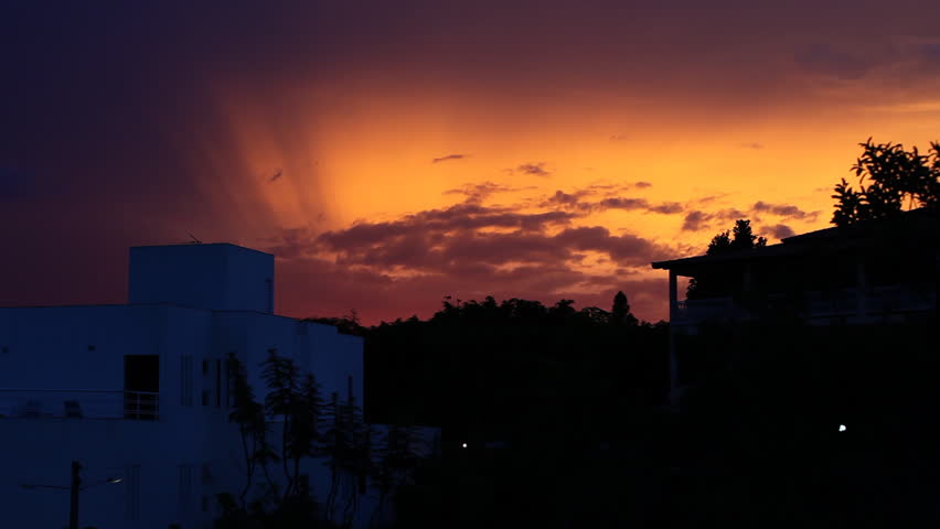 A post modern white villa in front of a dramatic sky during dusk