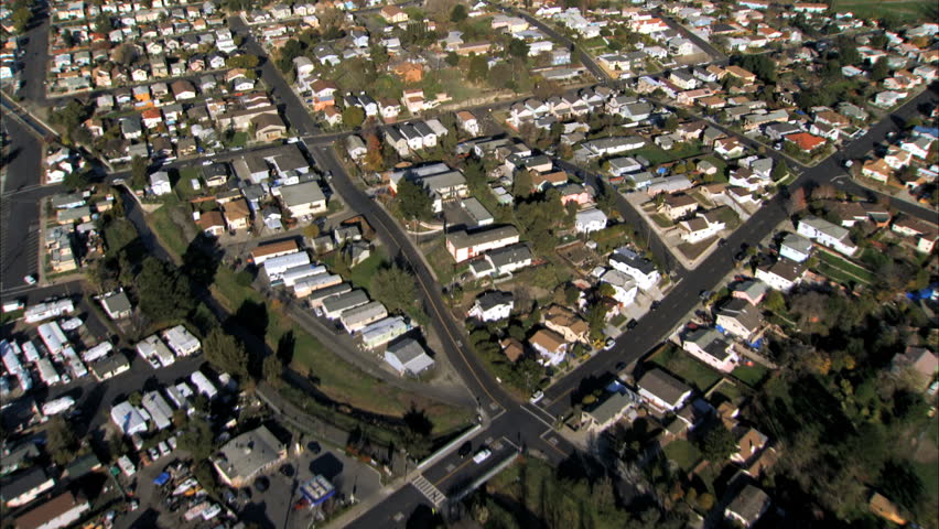Aerial view of rooftops of housing in city suburbs by industrial oil refinery