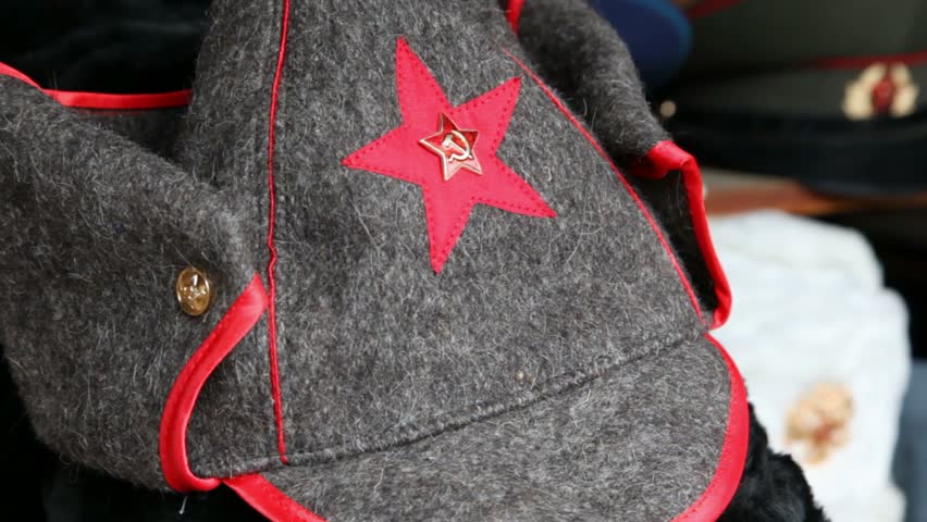 Many souvenir military caps with Soviet and Russian symbols and budenovka are on counter in a shop