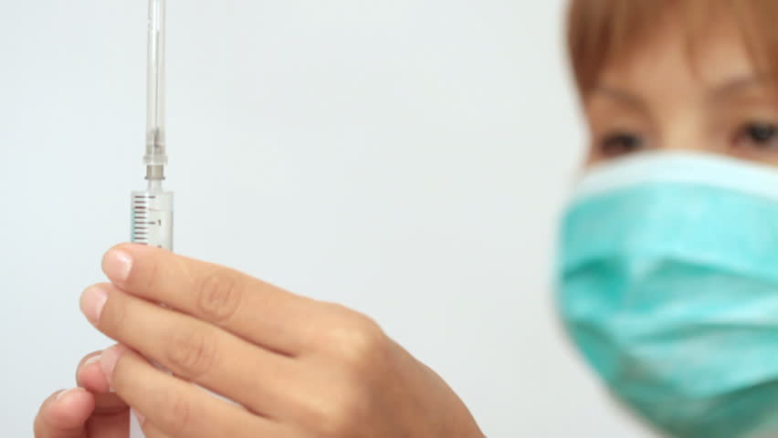 Nurse holds a syringe and prepares it for vaccination