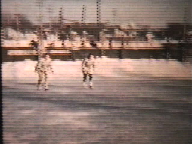 A couple of teenage girls enjoy some time ice skating at the local rink in the middle of winter.
