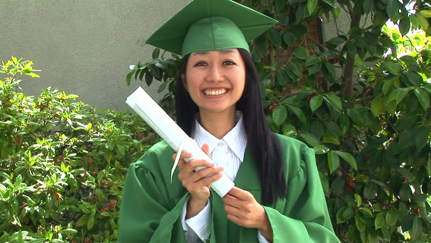 Young Asian woman in graduation gown with boyfriend outside 