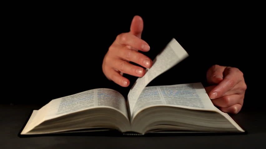 Hands and book over dark background