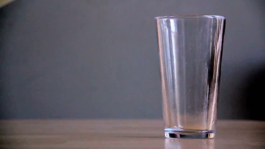 Slightly-slow-motion pour of milk into a pint glass. The empty jug is set down afterward.