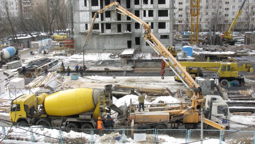 Work on a construction site: workers, a crane and cement mixer in Moscow, Russia.