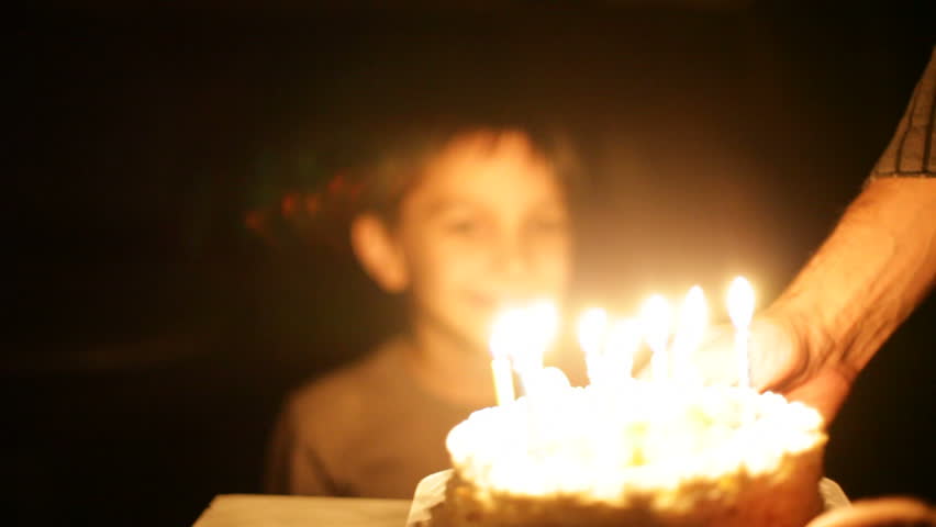 boy blows out candles on birthday cake. 