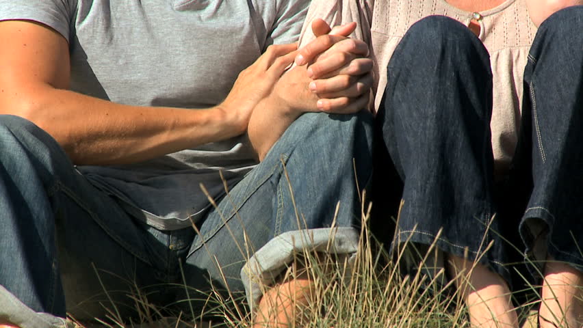Attractive young caucasian couple enjoying quiet time together sitting in sand dunes at the coast filmed at 60FPS