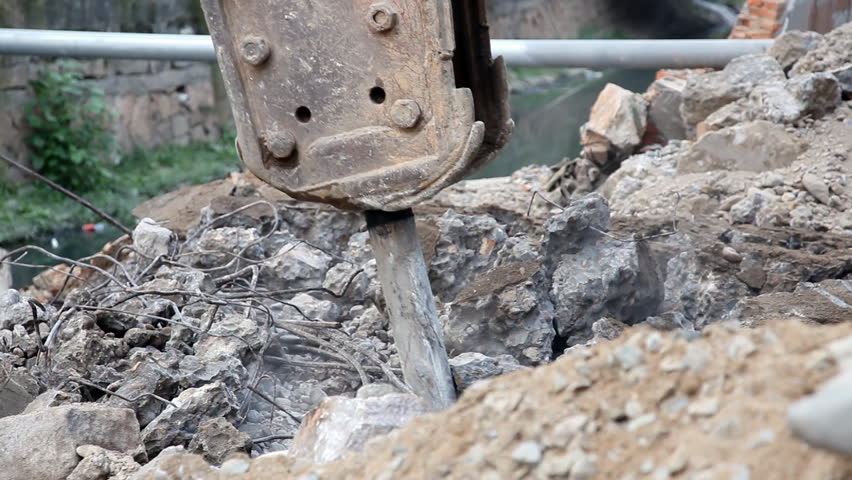 Crane breaking up stone into pieces to level the ground